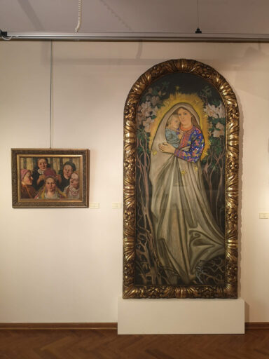 Sala ze sztuką secesyjną inspirowaną ludowością w muzeum. Na ścianie wisi duży prostokątny obraz zaokrąglony na górze, przedstawia sylwetkę Matki Boskiej z dzieciątkiem w ludowym stroju. To "Madonna wiejska" Stanisława Wyspiańskiego.