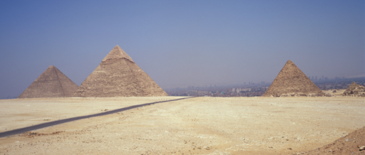 Pustynia pokryta żółtym piaskiem, nad nią niebieskie niego. Na linii horyzontu trzy piramidy, kamienne budowle w kształcie ostrosłupów. Dwie z nich są po prawej stronie, jedna po lewej.