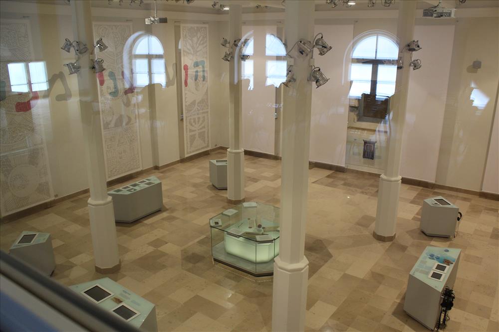 Sala Muzeum Żydów Mazowieckich, jasne ściany i podłoga, wysokie okna, kolumny i multimedialne kioski.
