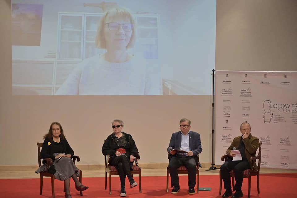 Aula muzeum, scena, na niej cztery krzesła. Siedzą na nich od lewej - Małgorzata Sady, Maya Gordon, Leonard Sobieraj, Andrzej Pościański. Za nimi na ścianie ekran, na nim widoczna Ingrid Blakestad.